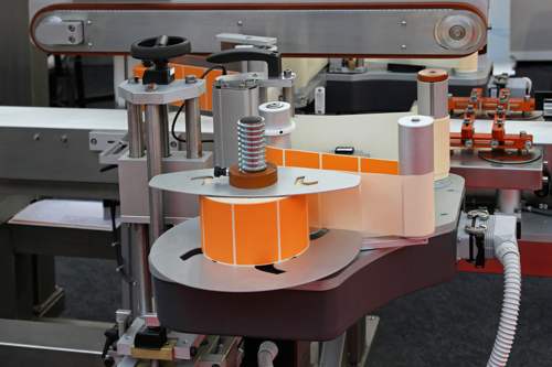 A machine creating orange whole custom labeling that will later be affixed to packaging